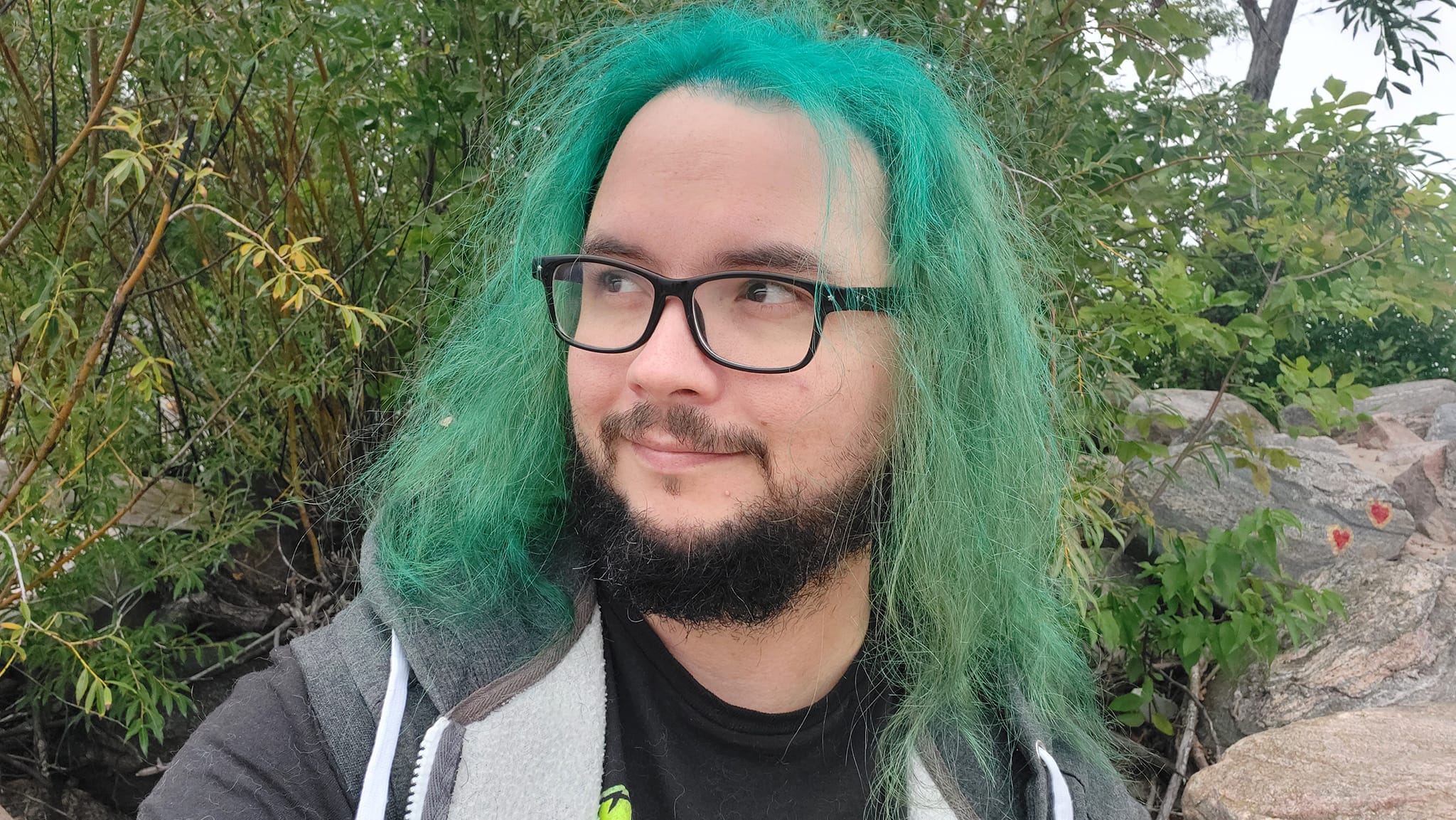 A man with green hair stands outside at a boulder breakwater, photo 6